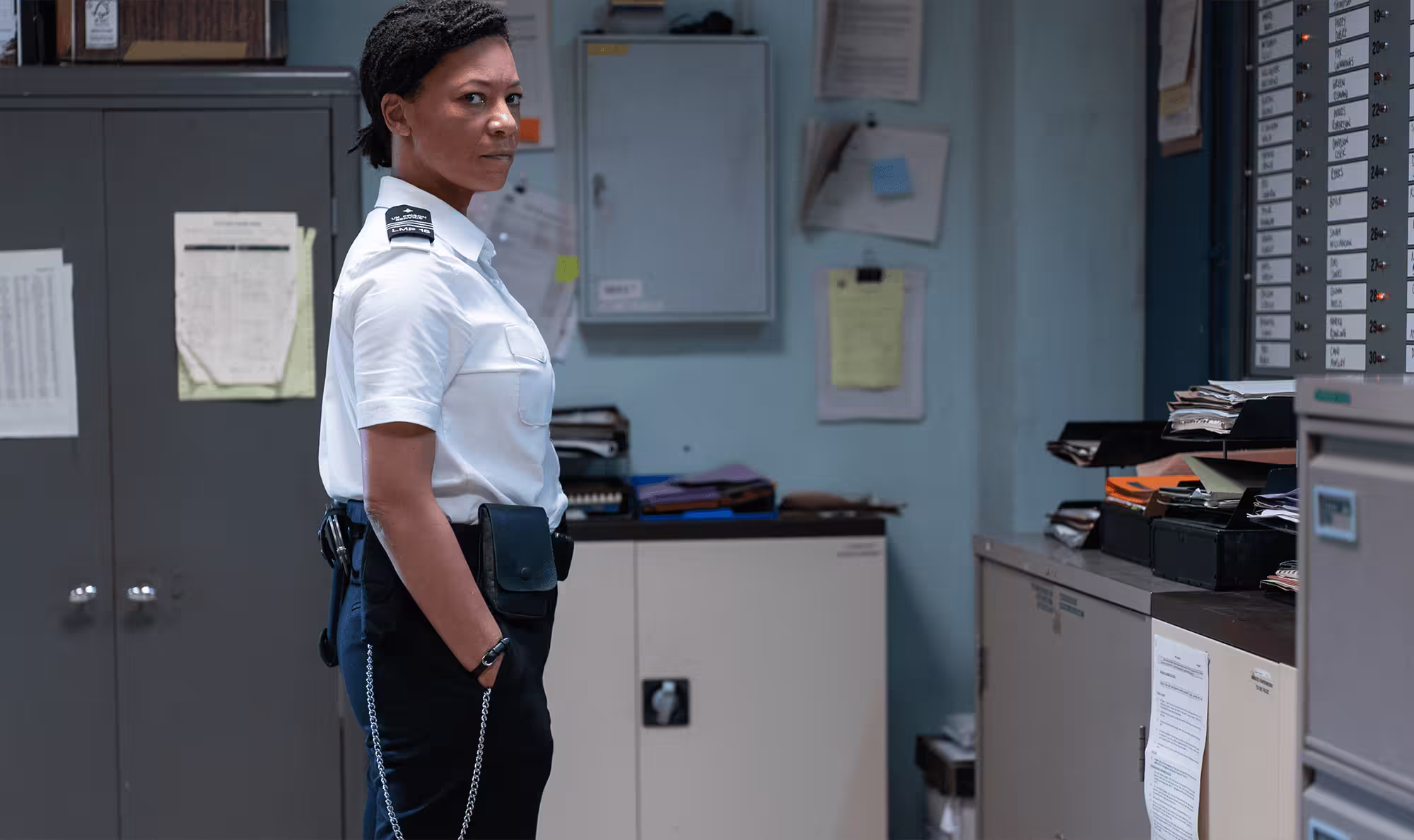 Woman in a prison officer outfit standing in a prison office.