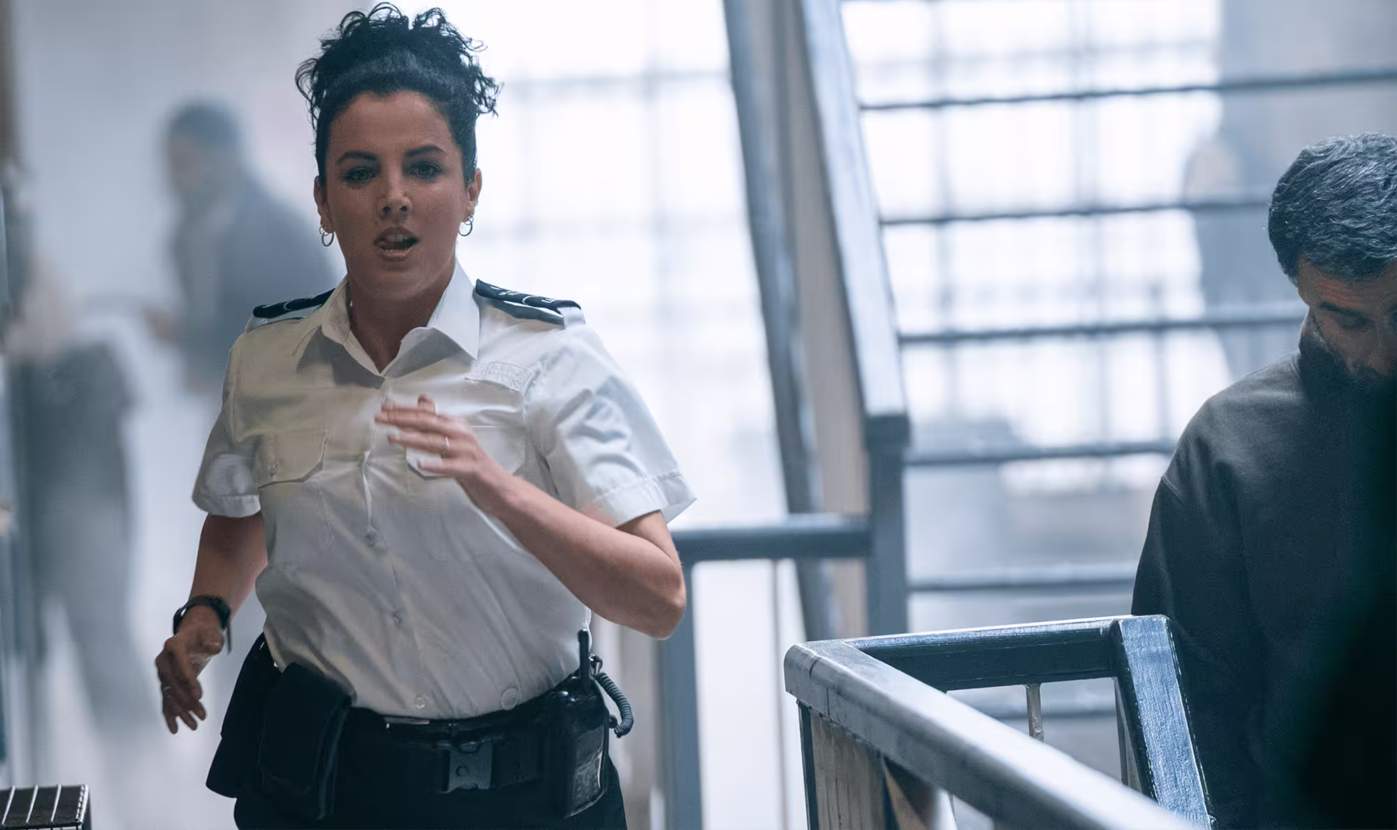Woman prison officer running through a cell block.