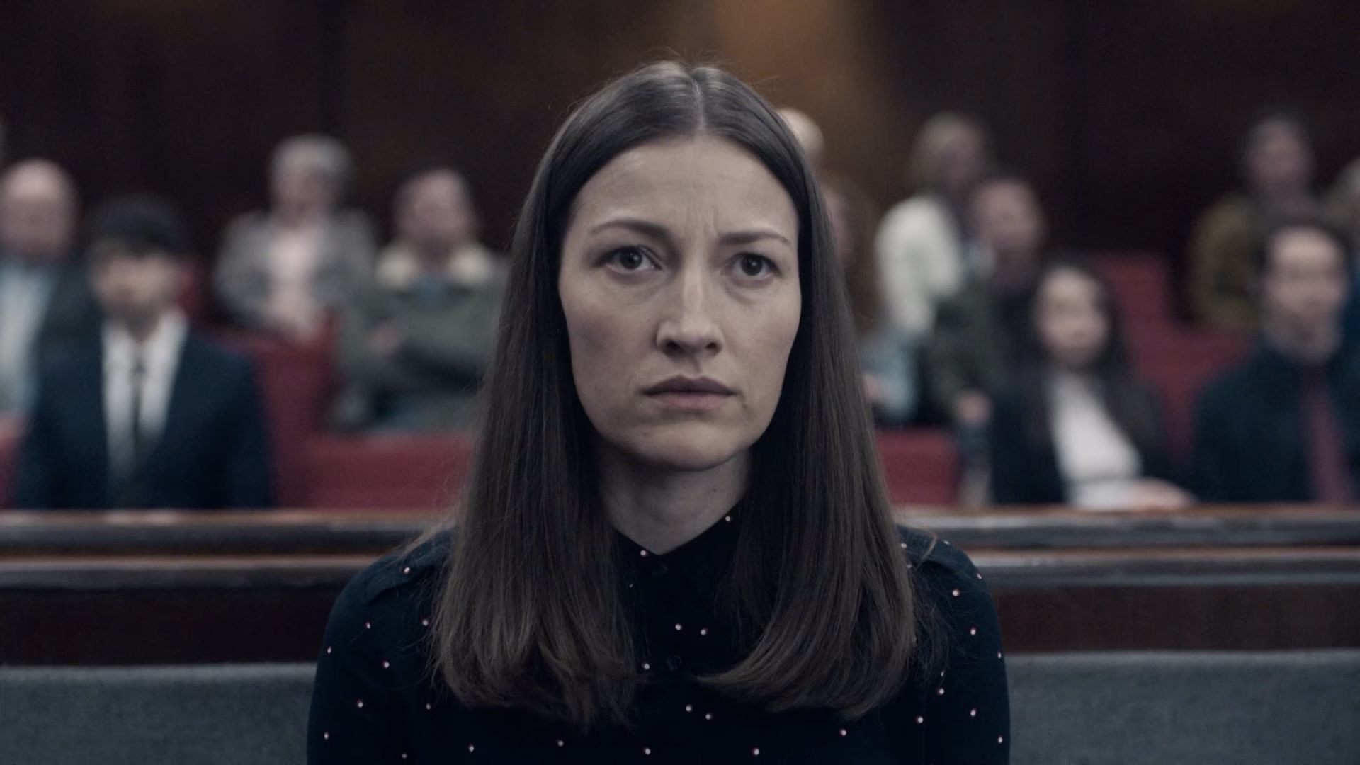 Woman in a courtroom setting looking concerned.